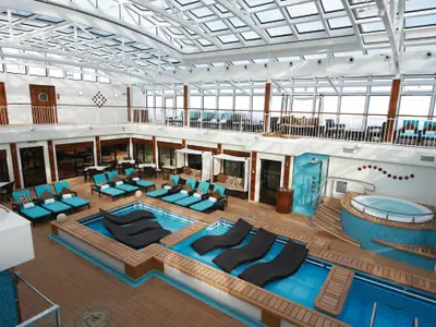 Blick von oben auf das helle, überdachte Pooldeck der Norwegian Breakaway. Zu sehen sind zwei Pools mit In-Pool-Liegen, türkise Sonnenliegen, Cabanas und ein Whirlpool.