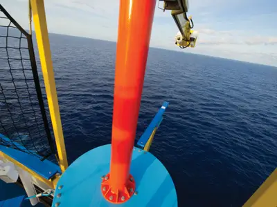Weitwinkelaufnahme vom Ropes Course der Norwegian Breakaway mit Blick auf das dunkelblaue Meer und einen hellen Himmel. Im Vordergrund sind bunte Bauteile des Schiffes zu sehen: eine orangefarbene Säule, blaue Plattformen, gelbe Balken und ein schwarzes Sicherheitsnetz.