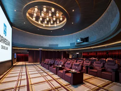 Ein moderner Kinosaal, das Silver Screen Bistro, an Bord der Norwegian Breakaway, mit Reihen bequemer, roter Liegesessel, die auf eine grosse Leinwand blicken. Deckenleuchten und Projektor sind sichtbar.