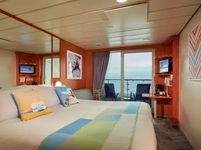 Eine helle Balkonkabine an Bord der Norwegian Dawn mit Doppelbett, TV und einem Balkon. Der Raum hat Meerblick und ist mit warmer Holzverkleidung und moderner Kunst ausgestattet.