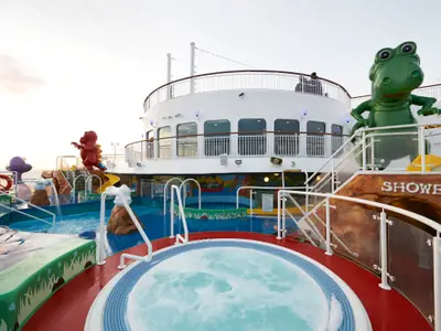 Bunter Kinder-Aquapark mit Wasserspielen, kleinen Rutschen und grossen Tierfiguren auf dem Sonnendeck der Norwegian Dawn. Ein Whirlpool ist im Vordergrund.
