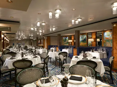 Das elegante Spezialitätenrestaurant Le Bistro an Bord der Norwegian Dawn. Es zeigt weiß gedeckte Tische, blaue Sitzbänke und Kunstwerke, die eine gehobene Atmosphäre schaffen.
