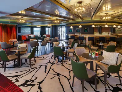 Die elegante Sugarcane Mojito Bar an Bord der Norwegian Encore. Der Raum ist mit bequemen Stühlen, Tischen, einer langen Bar mit Barhockern und warmen Lichtern ausgestattet.