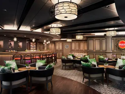 Elegante Sugarcane Mojito Bar an Bord der Norwegian Encore. Geschwungene Bar, bequeme Lounge-Sessel mit Palmenkissen, warme Holzvertäfelung und stilvolle Deckenleuchten. Das Sugarcane-Logo ist sichtbar. Keine Personen.