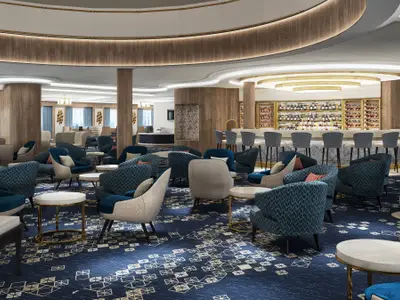 Das Rendering zeigt die Atrium Bar an Bord der Norwegian Encore. Eine elegante Lounge mit vielen blauen und beigefarbenen Sesseln, runden Tischen und einem Bartresen mit Hockern. Ein Weinregal und ein Klavier sind sichtbar.