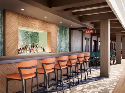 Blick auf die Sugarcane Mojito Bar an Bord der Norwegian Encore. Eine lange Bar mit orangefarbenen Barhockern ist unter einer ueberdachten Terrasse. Im Hintergrund viele Spirituosenflaschen und das Meer.
