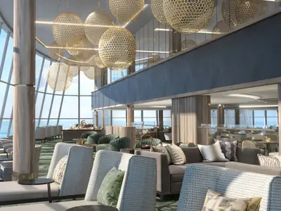 Die helle Observation Lounge der Norwegian Encore zeigt stilvolle Sitzbereiche und eine beeindruckende Glasarchitektur mit Blick auf das Meer. Goldene Hängelampen schmücken die hohe Decke.