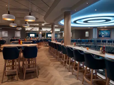 Innenansicht des Restaurants The Local Bar & Grill an Bord der Norwegian Encore mit modernen Möbeln und Beleuchtung.