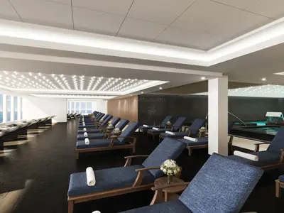 Blick in die helle und moderne Mandara Spa Thermal Suite der Norwegian Encore mit zahlreichen Liegestühlen und einem Hydro-Pool. Große Fenster bieten einen weiten Blick auf das offene Meer.