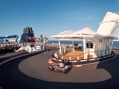 Go-Kart-Rennstrecke 'Encore Speedway' auf der Norwegian Encore. Go-Karts, Wasserrutschen und Meer unter blauem Himmel. Tageslicht.