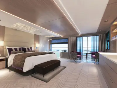 Eine luxuriöse Spa Suite an Bord der Norwegian Encore mit großem Bett, eleganter Holzvertäfelung und Meerblick. Eine Sitzecke und moderne Möbel sind ebenfalls zu sehen. Keine Personen.