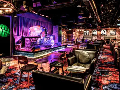 Eine stimmungsvolle Bar-Lounge im Cavern Club an Bord der Norwegian Epic. Eine beleuchtete Bühne mit Instrumenten und bequeme Sessel laden zum Verweilen ein.