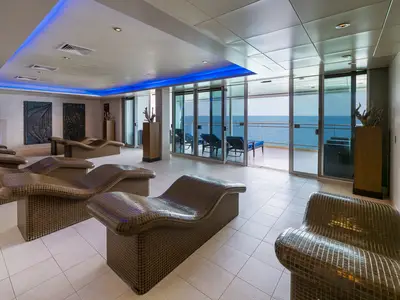 Mandara Spa Thermal Suite an Bord der Norwegian Epic. Ergonomische Mosaik-Liegen stehen vor einer Glasfront mit weitem Meerblick. Blaue Akzentbeleuchtung an der Decke.