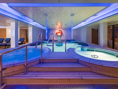 Das Mandara Spa Thermalbad an Bord der Norwegian Epic zeigt mehrere Whirlpools und Becken mit Wasserspielen und einer Decke mit Sternenlicht-Effekt. Die Szene wirkt entspannend.