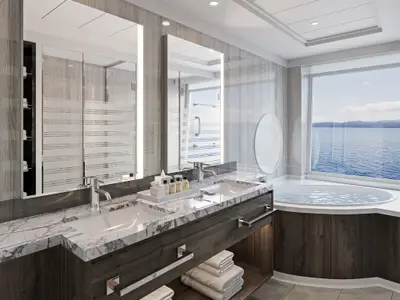 Elegantes Badezimmer an Bord der Norwegian Epic. Es verfügt über Doppelwaschbecken, eine Badewanne mit direktem Meerblick und moderne Elemente aus Marmor und Holz.
