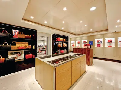 Innenansicht einer eleganten Boutique an Bord der Norwegian Escape, die hochwertige Handtaschen und Accessoires präsentiert. Die schwarzen Regale und hellen Vitrinen sind gut beleuchtet.