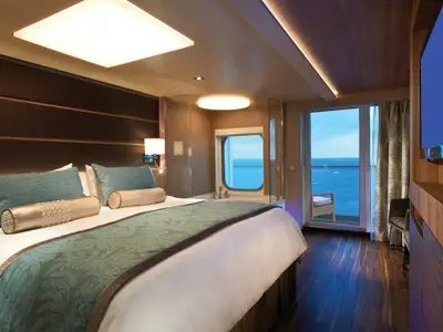 Blick in eine luxuriöse Suite an Bord der Norwegian Escape mit großem Bett, Badewanne am Panoramafenster und Zugang zum Meerblickbalkon.