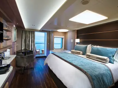 Geräumige Suite an Bord der Norwegian Escape mit Balkon, Badewanne am Fenster, Doppelbett und moderner Einrichtung.