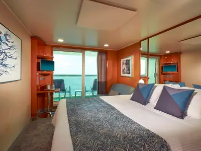 Eine helle und moderne Balkonkabine an Bord der Norwegian Gem. Großes Bett, Schreibtisch mit TV, Balkon mit Meerblick. Elegant eingerichtet.
