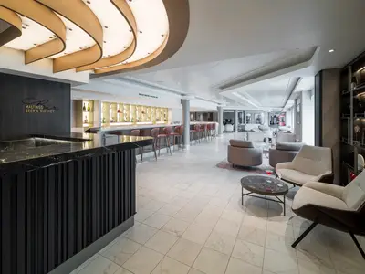 Die elegante "Maltings Beer & Whiskey" Bar an Bord der Norwegian Gem. Eine lange Marmorbar, Barhocker und bequeme Loungesessel prägen den modernen Raum mit stilvoller Beleuchtung.
