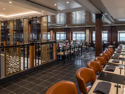Im Orchid Garden Spezialitätenrestaurant der Norwegian Gem: Elegante Tische, eine Sushi-Bar und Meerblick durch große Fenster. Die moderne Einrichtung ist von asiatischen Holzelementen geprägt.