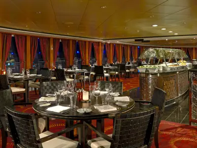 Elegantes Spezialitätenrestaurant Moderno an Bord der Norwegian Gem. Festlich gedeckte Tische und ein Buffetbereich bei warmer Abendstimmung.