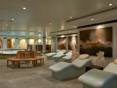 Der Thermalbereich an Bord der Norwegian Gem mit Whirlpools, einer runden Holzbank und bequemen Relaxliegen. Der Raum ist mit grossen Pflanzenbildern und Statuen dekoriert.