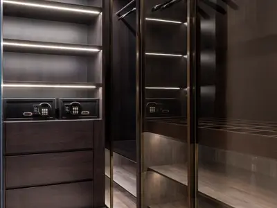 Ein modern gestalteter Kleiderschrank mit integrierter LED-Beleuchtung und zwei schwarzen Safes an Bord der Norwegian Gem. Dunkles Holz und klare Linien verleihen dem Bereich ein elegantes Aussehen.