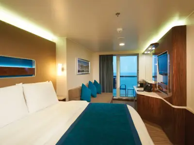 Eine elegante Balkonkabine an Bord der Norwegian Getaway mit einem großen Bett, einem Sofa, einem Fernseher und einem Balkon mit Meerblick.
