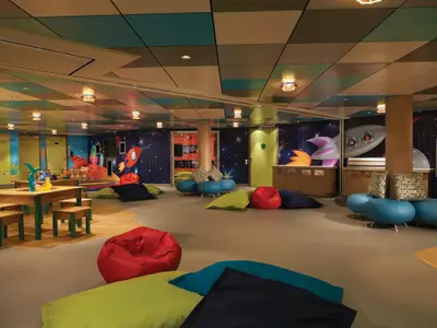 Ein farbenfroher Kinderbereich, die Splash Academy, an Bord der Norwegian Getaway. Der Raum ist mit Weltraum-Wandmalereien, kleinen Spieltischen und zahlreichen farbigen Sitzsäcken ausgestattet.