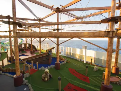 Minigolfplatz und mehrstufiger Hochseilgarten auf dem Deck der Norwegian Getaway. Die Anlage ist von der Abendsonne beleuchtet, mit weitem Meer im Hintergrund.