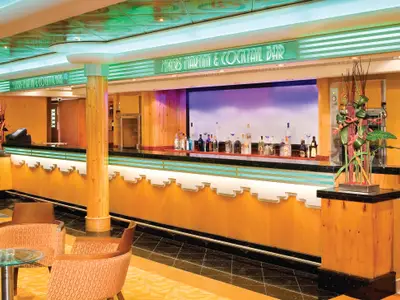 Die Mixers Martini & Cocktail Bar an Bord der Norwegian Jade zeigt eine lange, elegant beleuchtete Theke mit vielen Flaschen. Modernes Design mit Holzverkleidungen und grünen Akzenten.