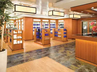 Ein eleganter Spa-Shop an Bord der Norwegian Jade. Im Vordergrund stehen Holzregale mit Produkten, im Hintergrund eine Rezeption mit einem Yin-Yang-Symbol an der Tür. Bambuspflanzen schmücken den Raum.