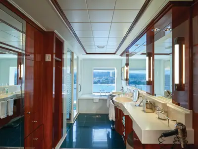 Geräumiges, luxuriöses Bad an Bord der Norwegian Jade. Es verfügt über einen Doppelwaschtisch, eine tiefe Badewanne am Fenster mit Meerblick und Holzvertäfelungen.