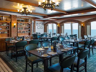 Das elegante italienische Restaurant La Cucina an Bord der Norwegian Jewel. Mit dunkelgrünen Stühlen, Holztischen und rustikalen Backsteinbögen, die Meerblick bieten.