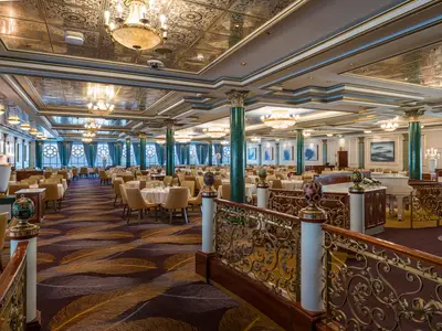 Der grosszügige "Tsars Palace" Speisesaal an Bord der Norwegian Jewel, mit elegant gedeckten Tischen, opulenten Kronleuchtern und grünen Marmorsäulen.