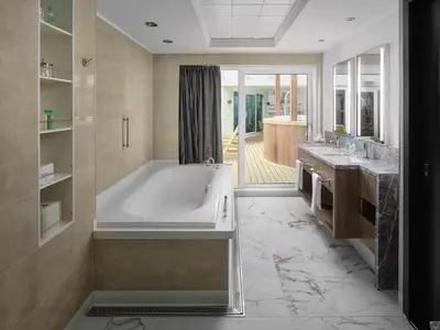 Geräumiges, modernes Badezimmer an Bord der Norwegian Jewel mit großer Badewanne, Doppelwaschtisch und Zugang zu einer privaten Terrasse mit Whirlpool.