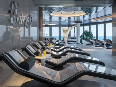 Helle und moderne Spa-Entspannungslounge an Bord der Norwegian Joy. Komfortable Liegen mit Meerblick laden zum Verweilen ein. Getränke stehen bereit.
