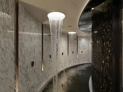 Ein modernes Spa mit mehreren eleganten Erlebnisduschen, die Wasser von der Decke fallen lassen, und stilvollen Fliesen in Schwarz und Weiss an Bord der Norwegian Joy.