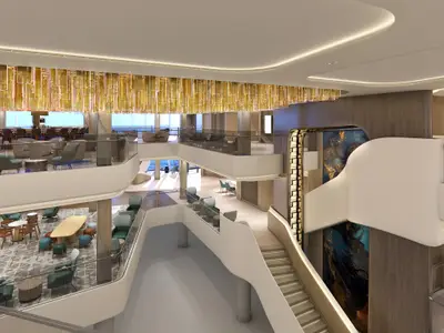 Modernes, mehrstöckiges Atrium an Bord der Norwegian Luna mit Lounges, Bar, Meerblick und einer kunstvollen Treppe. Eine goldene Deckenbeleuchtung ziert den Raum.