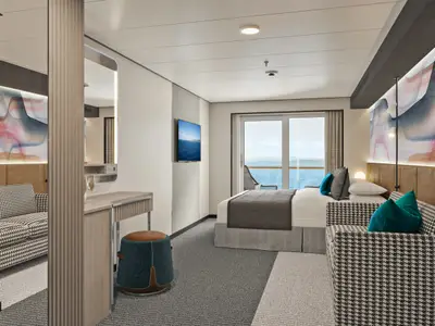 Moderne Balkonkabine an Bord der Norwegian Luna mit großem Bett, gemütlicher Sitzecke, Schreibtisch und Balkon mit Meerblick. Helle, stilvolle Einrichtung mit Kunst an der Wand.