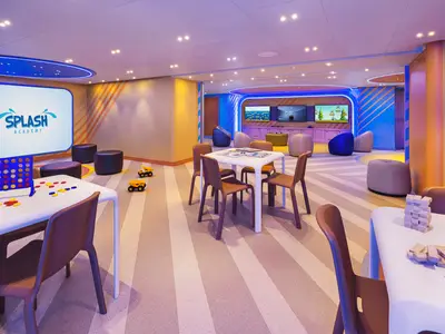 Der farbenfrohe Kinderbereich "Splash Academy" an Bord der Norwegian Luna zeigt Spieltische, weiche Sitzgelegenheiten und eine Gaming-Ecke. Das moderne Interieur ist hell und einladend.