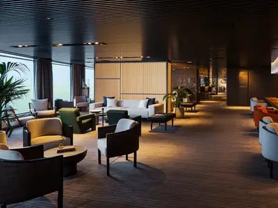 Elegante Haven Lounge an Bord der Norwegian Luna. Mehrere Sitzbereiche mit modernen Sesseln, Sofas und Tischen. Große Fensterfront mit Meerblick, Holzelemente und Pflanzen. Warme, indirekte Beleuchtung.