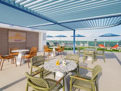 Eine lebhafte Outdoor-Lounge im Horizon Park an Bord der Norwegian Luna. Helle Tische, geflochtene Stühle und Liegestühle auf Kunstrasen bieten Meerblick unter einem blauen Lamellendach.