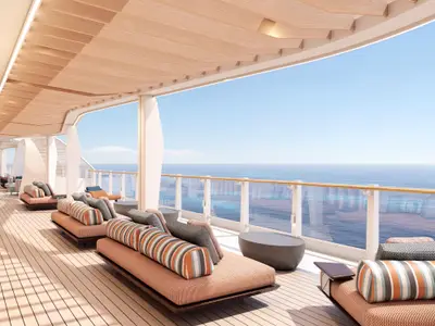 Weitwinkelaufnahme der modernen La Terraza Outdoor-Lounge an Bord der Norwegian Luna. Zahlreiche bequeme Liegen mit gestreiften Kissen bieten einen weiten Blick auf das offene Meer.