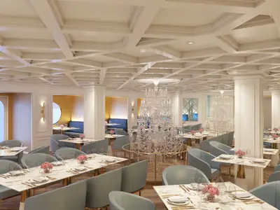 Ein elegantes Restaurant an Bord der Norwegian Luna mit vielen Tischen, hellblauen Stühlen, opulenten Kristallleuchtern und einer ansprechenden Inneneinrichtung in Weiß- und Goldtönen. Eine moderne und luxuriöse Atmosphäre ist erkennbar.