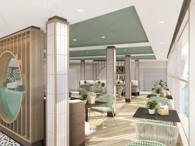 Ein lichtdurchflutetes Restaurant an Bord der Norwegian Luna. Helle Holzpaneele und grüne Akzente schaffen eine moderne Atmosphäre. Zahlreiche Tische und Stühle sind zu sehen, dazu große Fenster mit Blick auf das Meer und die Küste.