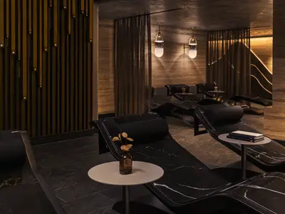 Luxuriöser Spa-Ruhebereich der Norwegian Luna. Schwarze Marmorliegen, Beistelltische. Elegante Wände mit vertikalen Lichtinstallationen schaffen eine entspannende Atmosphäre.