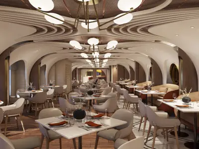Elegantes Spezialitätenrestaurant Onda by Scarpetta an Bord der Norwegian Luna. Moderner Speisesaal mit geschwungenen Wänden, stilvollen Tischen und warmer Beleuchtung. Keine Personen.