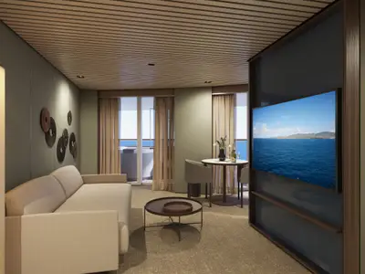 Modernes Wohnzimmer einer luxuriösen Suite an Bord der Norwegian Luna mit beigem Sofa, Couchtisch, Esstisch und großem Fernseher. Glastüren zum Balkon bieten Meerblick.